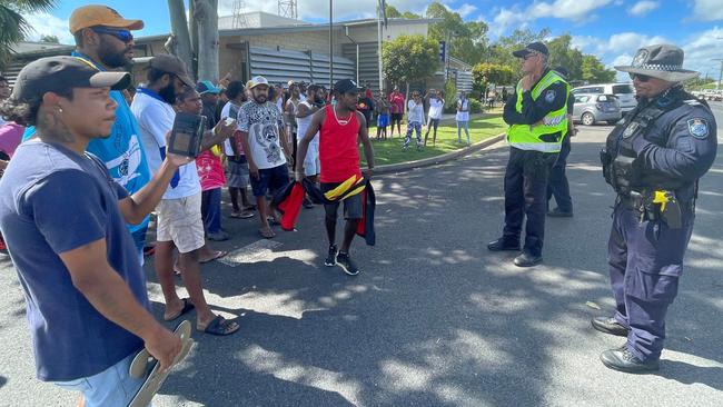 Protester Steven Douglas, dressed in red, faces off with police outside the Mareeba police station on Monday morning.