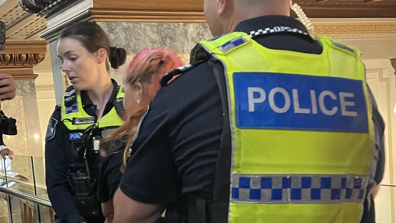 A protester who volunteers for Greens candidate for Moreton Remah Naji is detained by police in the council chamber.