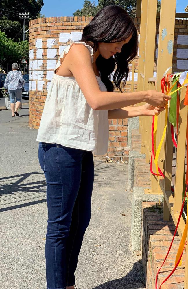 Meghan, Duchess of Sussex ties on a ribbon as she visits the memorial to murdered South African student Uyinene Mrwetyana in Cape Town. Picture: AFP