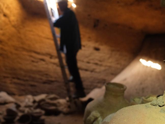 A handout picture provided by the Israel Antiquities Authority on Septembre 18, 2022, shows an archaeologist first entering a funerary cave discovered at the central Palmachim park area on the Mediterranean coast, containing untouched finds such as  pottery vessels, dating back to the thirteenth century BCE during the rule of Egypt's Pharaoh Rameses II. - The cave was uncovered on a beach earlier in the week, when a mechanical digger working at the Palmahim national park hit its roof, with archaeologists using a ladder to descend into the spacious, man-made square cave. (Photo by Emil Aladjem / Israeli Antiquities Authority / AFP) / RESTRICTED TO EDITORIAL USE - MANDATORY CREDIT "AFP PHOTO / HO / ISRAEL ANTIQUITIES AUTHORITY" - NO MARKETING NO ADVERTISING CAMPAIGNS - DISTRIBUTED AS A SERVICE TO CLIENTS