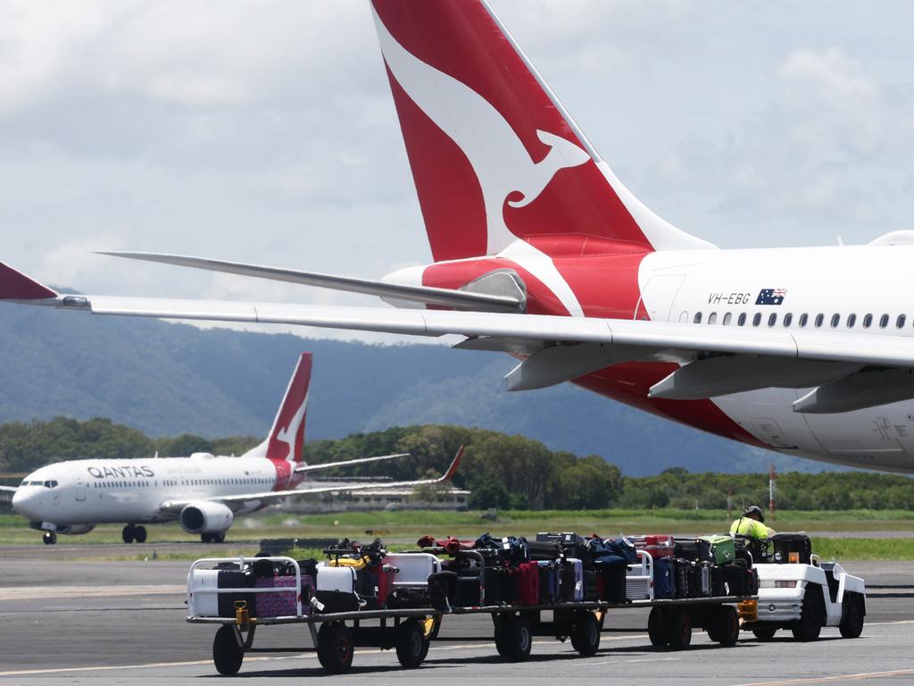 A baggage handler waits for a Qantas Boeing 737 passenger jet aircraft to taxi on the tarmac apron at Cairns Airport, ready to take tourists and local passengers to southern Australian destinations. Picture: Brendan Radke