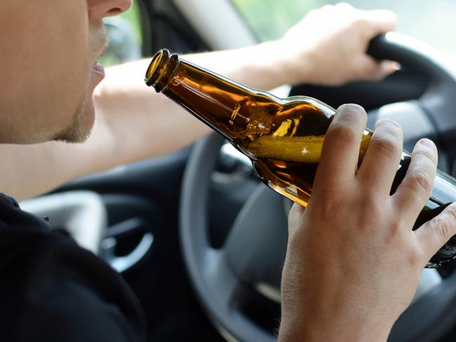 The concept of alcohol driving crime - closeup of young male driver hands with steering wheel and bottle of beer. Drink driving generic. Picture: iSTOCK