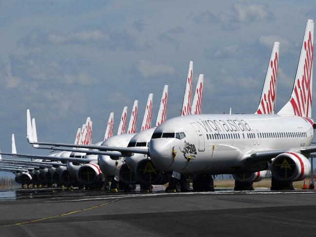 Grounded Virgin Australia aircraft are seen parked at Brisbane Airport in Brisbane, Tuesday, April 7, 2020. Brisbane Airport Corporation (BAC) is working with airlines by accommodating up to 100 grounded aircraft free of charge in response to government-mandated travel restrictions that have grounded a significant proportion of Australia's airline fleet because of the Coronavirus (COVID-19). (AAP Image/Darren England) NO ARCHIVING