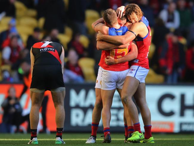 MELBOURNE, AUSTRALIA - JULY 02:  Tom Rockliff of the Lions (C) is hugged by Dayne Zorko and Eric Hipwood (R) after their winon the final siren during the round 15 AFL match between the Essendon Bombers and the Brisbane Lions at Etihad Stadium on July 2, 2017 in Melbourne, Australia.  (Photo by Michael Dodge/Getty Images)