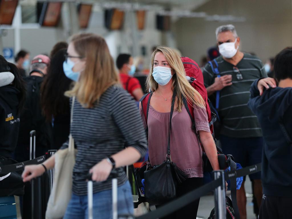 People wear masks at a packed Sydney Airport departures terminal this morning. Picture: David Swift