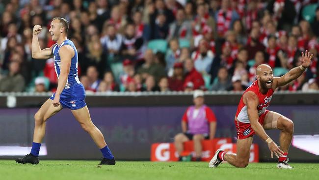 North Melbourne’s Billy Hartung celebrates kicking a goal as Jarrad McVeigh of the Swans appeals for a touch at the SCG on Saturday night. Picture: Getty Images