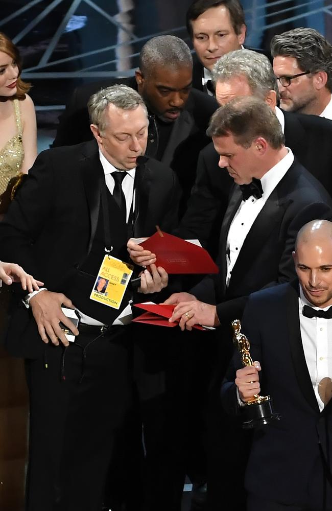 La La Land producer Fred Berger speaks at the microphone as production staff and representatives from PricewaterhouseCoopers scrambled on stage to work out what happened. Picture: Getty Images