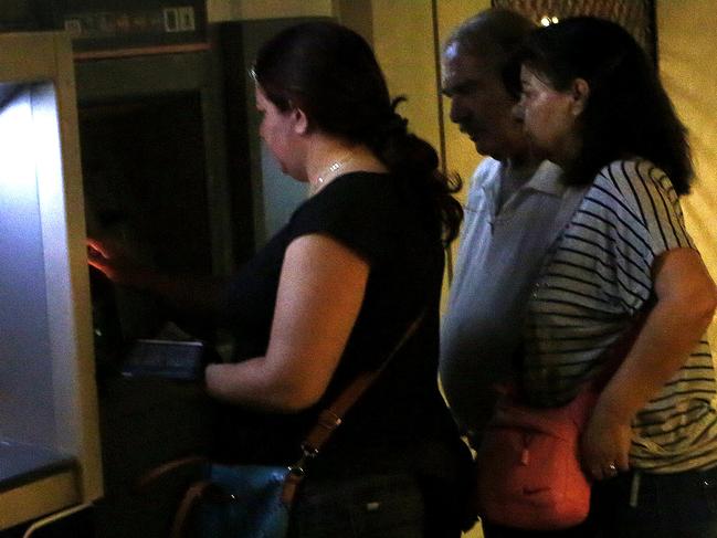 A couple passes by the ATM machines used by people in Monastiraki in Athens, early Monday, June 29, 2015. Greece's five-year financial crisis took its most dramatic turn to date Sunday, with Prime Minister Alexis Tsipras announcing Greek banks would remain shut indefinitely and restrictions would be imposed on cash withdrawals. (AP Photo/Petros Karadjias)