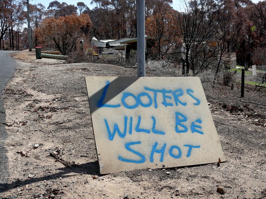 A sign on Ridge Ave in Malua Bay warning looters will be shot if found going through the remains of homes affected by the recent bushfires. Picture: Toby Zerna