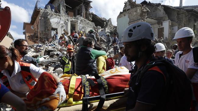 Rescuers recover a victim from a crumbled building in Amatrice, central Italy. Picture: Alessandra Tarantino.