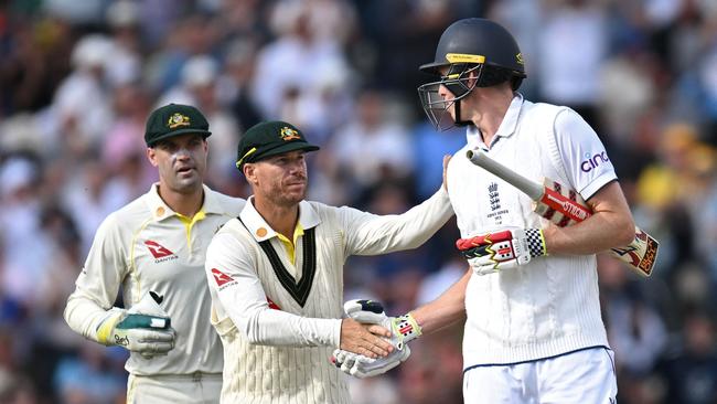 David Warner (C) shakes the hand of England's Zak Crawley (R) after he loses his wicket for 189 runs.