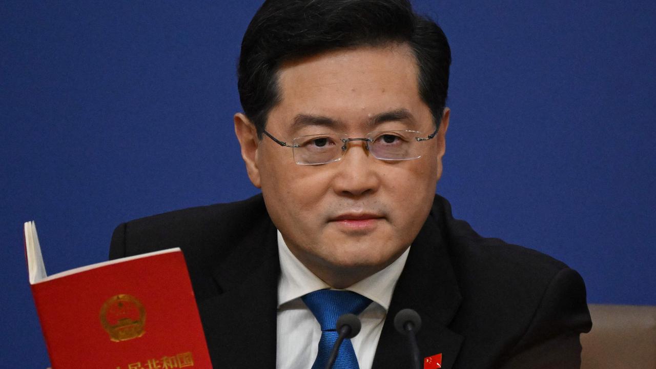 China's foreign minister Qin Gang holds a copy of China's constitution during a press conference. (Photo by NOEL CELIS / AFP)