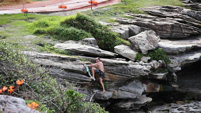 People ignore closure signs and fences at MacKenzies Bay on the Bondi to Bronte walk this morning. Picture: Adam Yip