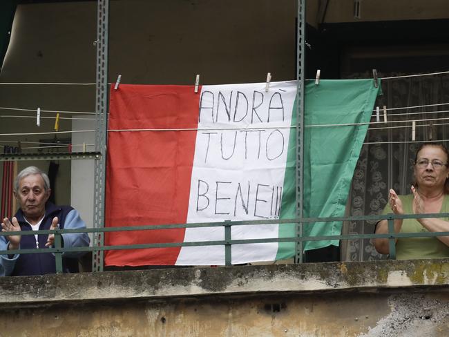 A couple applauds next to an Italian flag reading everything will be all right, at the Garbatella neighbourhood, in Rome. Picture: AP