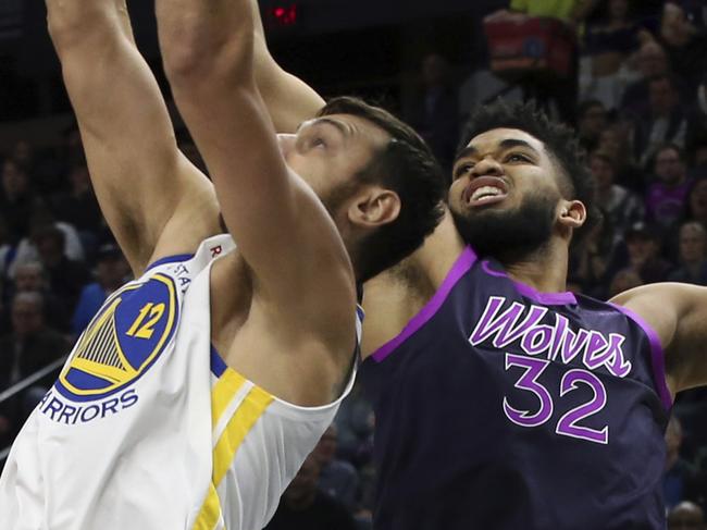 Golden State Warriors' Andrew Bogut, left, beats Minnesota Timberwolves' Karl-Anthony Towns to a rebound in the first half of an NBA basketball game Tuesday, March 19, 2019, in Minneapolis. (AP Photo/Jim Mone)