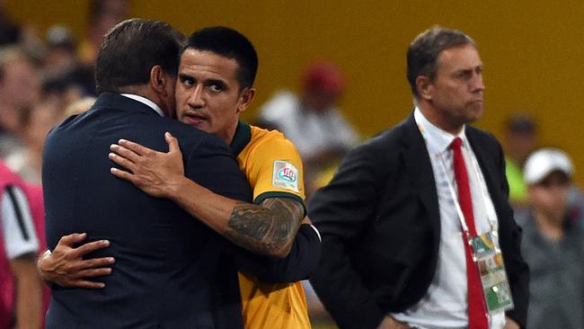 Australia's Tim Cahill (C) hugs his team coach Ange Postecoglou (L).