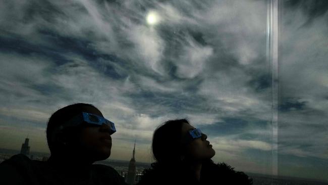 People look toward the sky at the 'Edge at Hudson Yards' observation deck during a total solar eclipse across North America, in New York City. Picture: Charly TRIBALLEAU / AFP)