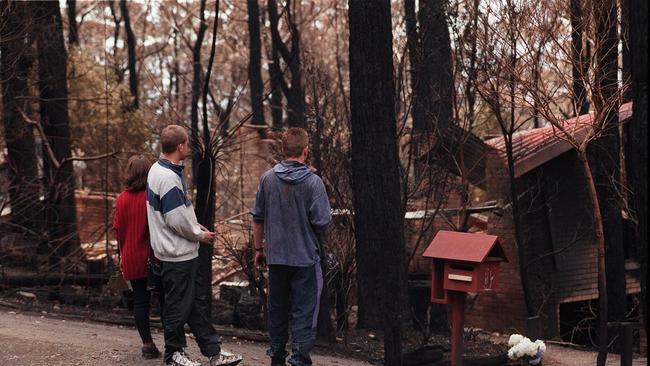 Jennifer Lindroth's brothers and family friend look onto the burnt house in Seabreaze Ave in Ferny Creek.