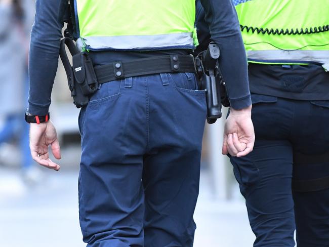 Victorian Police officers are seen carrying gun holsters outside the State Library of Victoria building in Melbourne on Friday, August 4, 2017. Victoria Police confirmed they have recalled 18,000 custom-made gun holsters to be modified after problems were identified during training last week. (AAP Image/ James Ross) NO ARCHIVING