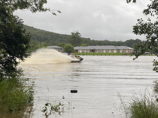 Two daring young boys zipping around on a jetski at the front of a flooded property opposite Treetops Adventure Park. Picture: Dana Pendrick