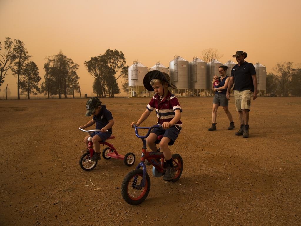 Fourth generation farmer Brad Cox with his wife Katie Cox and their children Georgia Cox, 4 months, James Cox, 2, and Edward Cox, 5, on their property near Collie, north of Dubbo, during a dust storm. Currently in the midst of the worst drought their worst drought on record, they farm sheep, cattle and grain. Picture: Dylan Robinson