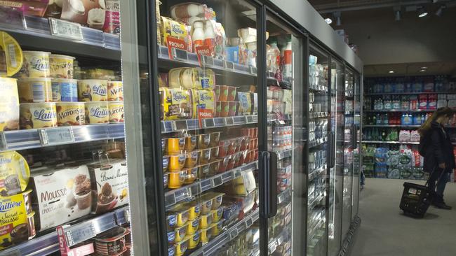 A woman walks next to a yoghurt refrigerator in a supermarket in Paris, Thursday, March 12, 2015. France's competition authority handed the country's top yogurt makers 192 million euros ($203 million) in fines Thursday for fixing prices over the course of several years, striking secret deals in hotel rooms and on special phone lines created to avoid detection. (AP Photo/Michel Euler)