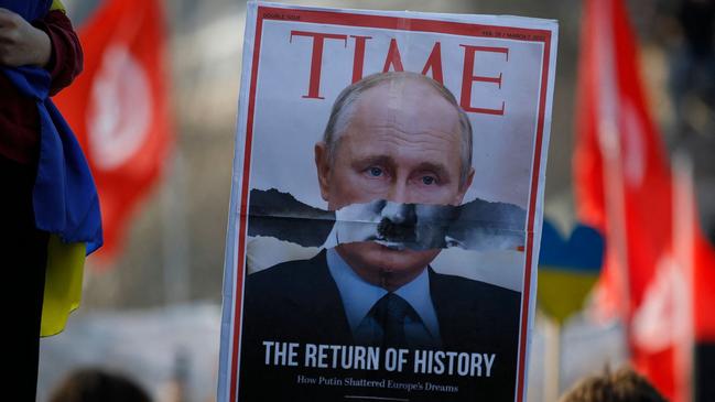 A magazine cover with Vladimir Putin's face with the mustache of Adolf Hitler is held aloft during an anti-war protest.