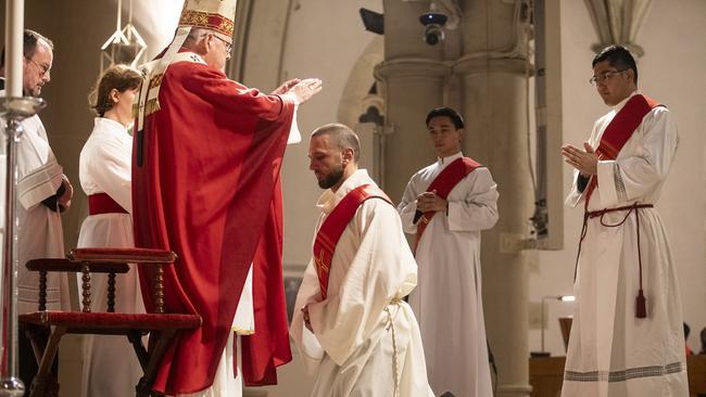 Archbishop Coleridge prays with Father Falzon at the ordination, with Father Lai and Father Kim looking on. Picture: Natalie Grono