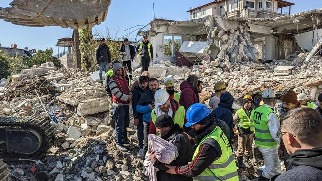 Miners from Zonguldak walk with a man carrying his child's body they extracted from rubble, as they carry out search operations in Antakya. Picture: AFP