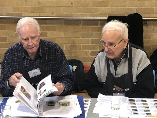 John Coye (left) and Peter Rudland, a co-founder of Men’s Kitchen, look through a recipe folder during a Men's Kitchen Northern Beaches cooking skills session. Picture: Jim O'Rourke