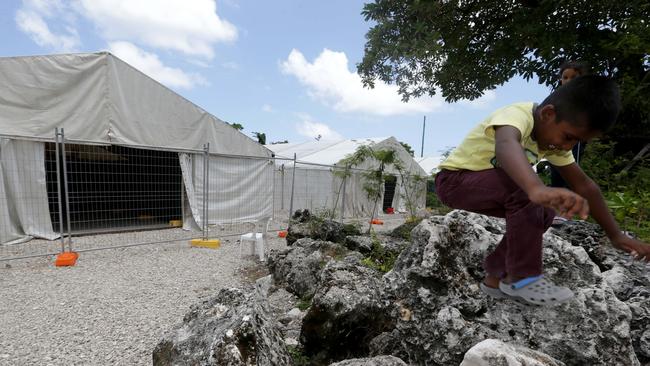 A young boys stands on the rocks by the tents in camp PC2 at Nauru.