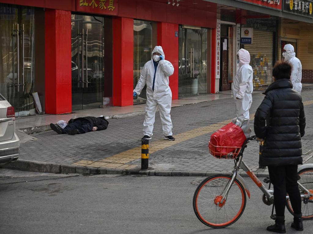 This photo taken on January 30, 2020 shows officials in protective suits checking on an elderly man who collapsed and died on a street near a hospital in Wuhan. Picture: Hector Retamal/AFP