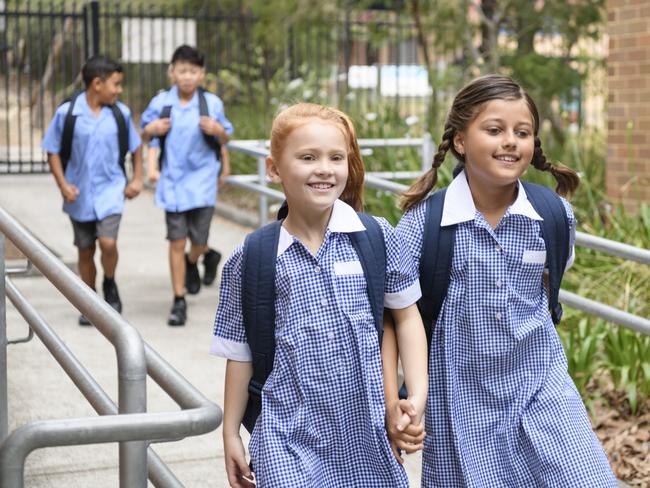 Female primary school students wearing blue gingham dresses with boys in background