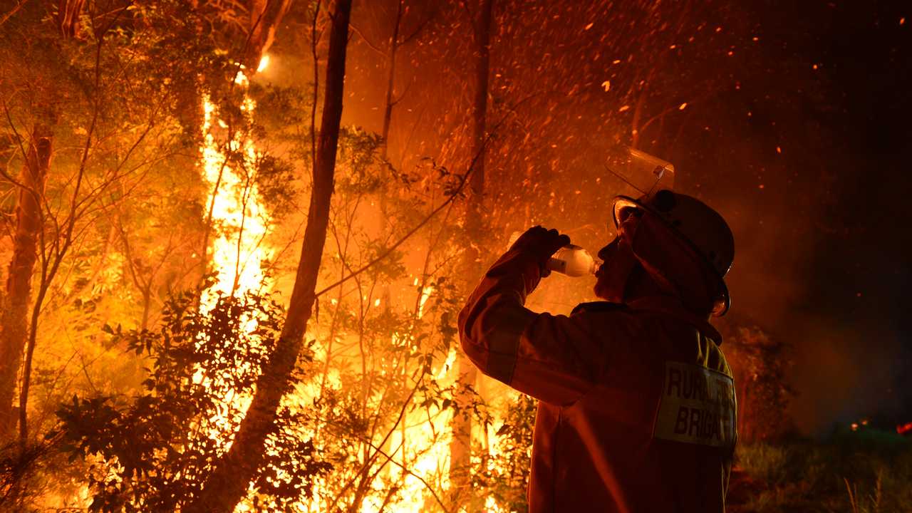 A firefighter takes a much needed drink amidst the heat of a back burn at Peregian Springs. Photo John McCutcheon