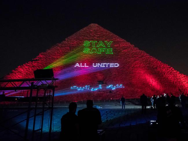 People take pictures of the Great pyramid of Kheops where a laser projection writes “Stay home, all united” due to the coronavirus. Picture: Khaled Desouki/AFP