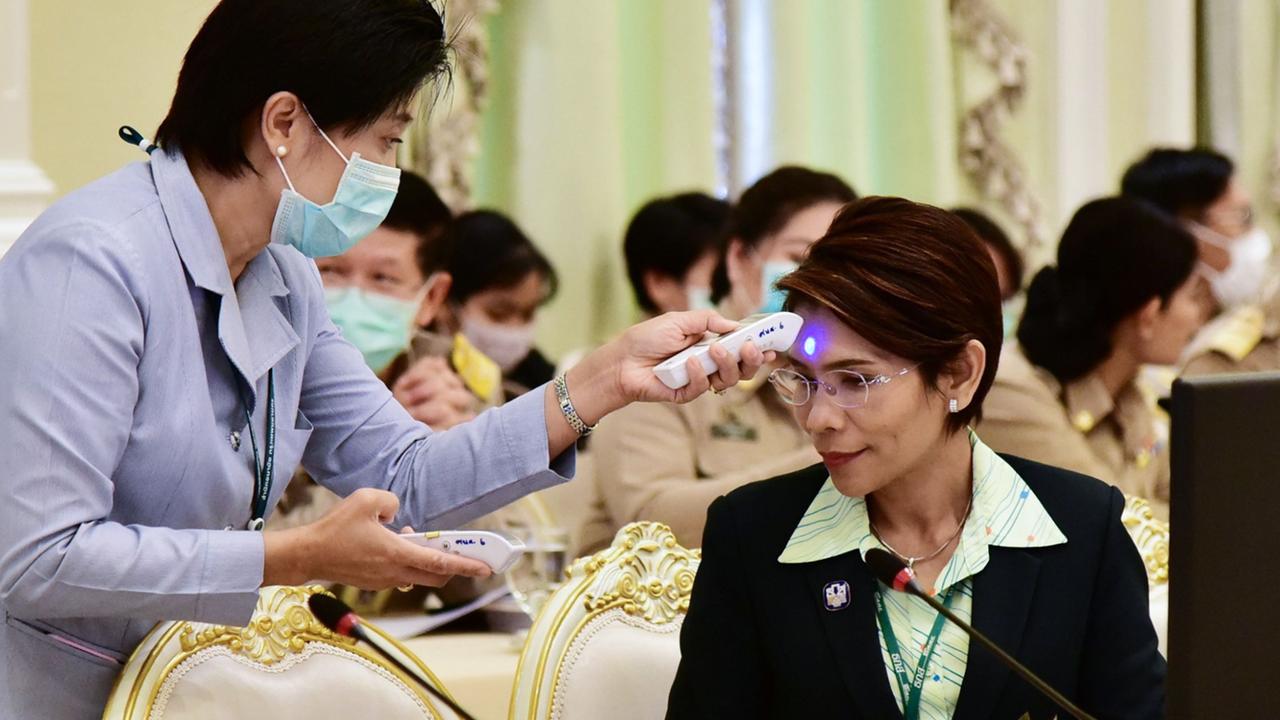 A paramedic checks the temperature of a government official before a meeting with Thailand Prime Minister Prayut Chan-O-Cha at the Government House in Bangkok. Picture: Royal Thai Government/AFP