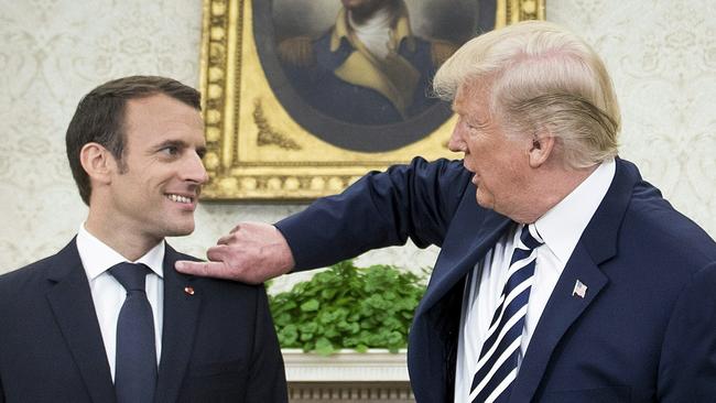 US President Donald Trump (R) clears dandruff from French President Emmanuel Macron's shoulder in the Oval Office before a meeting at the White House April 24, 2018 in Washington, DC. / AFP PHOTO / Brendan Smialowski