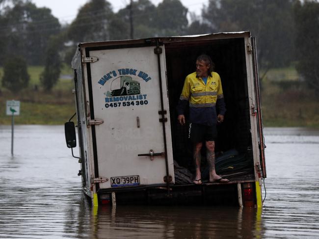 A man gets help from his neighbour to rescue his truck on Elizabeth MacArthur Ave, Camden South on Sunday morning. Picture: Jonathan Ng