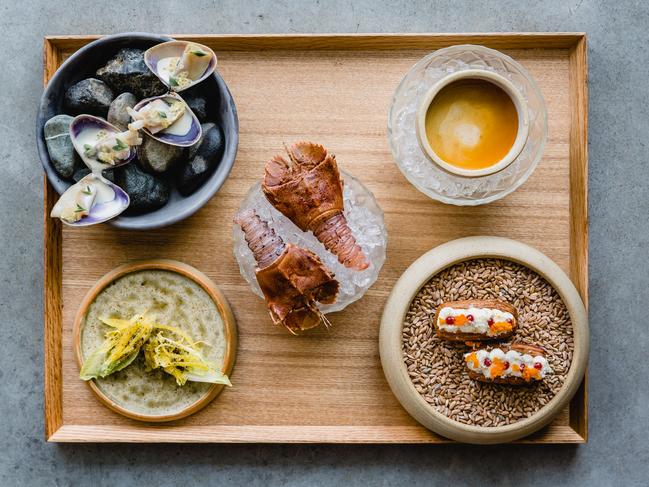 Pipit’s ‘seasonal snacks’ featuring baby bay lobster with bunya nut tamari and mountain pepper (centre) and (clockwise from top left) grilled pipis with macadamia milk, fingerlime and sea purslane, smoked flathead finger bun with ooray plum and bay lobster caviar; and yellow endive with cured emu egg yolk. Picture: Sabine Bannard