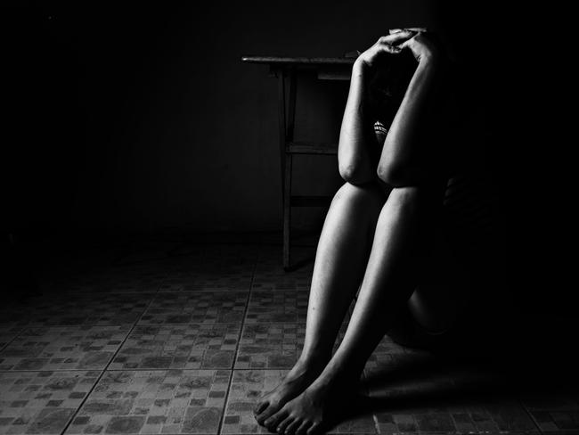 a woman sitting on ground with arm around lower head, sexual violence , sexual abuse, human trafficking concept with shadow edge in white tone, rape. Picture: iSTOCK