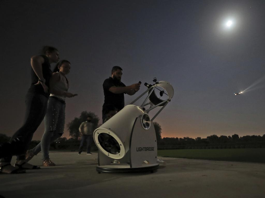 People stand to watch a partial lunar eclipse through a telescope at the Al Thuraya Astronomy Center in Dubai, United Arab Emirates, Tuesday, July 16, 2019. (AP Photo/Kamran Jebreili)