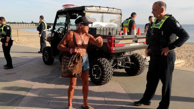 Police talk with beachgoers at St Kilda on Friday. Picture: David Geraghty.