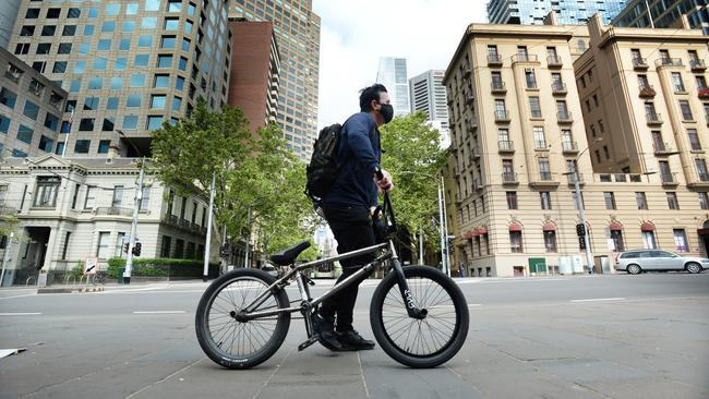 A person wearing a mask at the top of Collins Street in Melbourne - which is now somewhat of a ghost town. Picture: NCA NewsWire / Andrew Henshaw