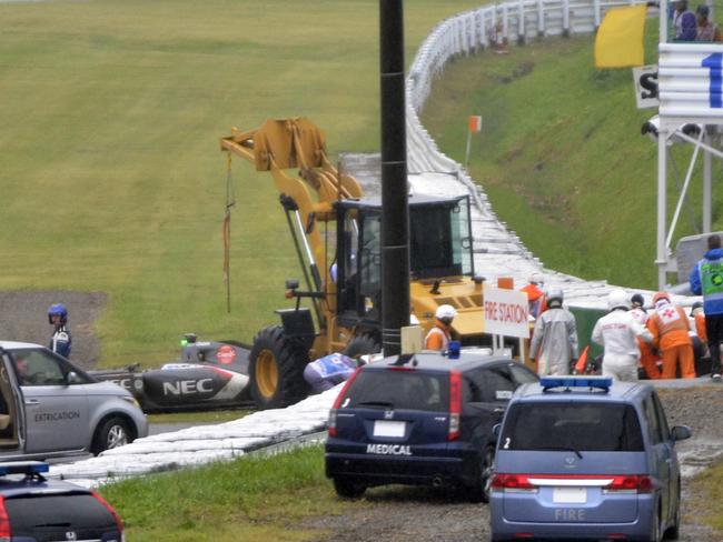 In this Sunday, Oct. 5, 2014 photo, rescuers and others gather around the car of Marussia Formula One driver Jules Bianchi after crashing during the Japanese Formula One Grand Prix at the Suzuka Circuit in Suzuka, central Japan. Bianchi was unconscious when he was taken to a nearby hospital following a crash during Sunday's rain-shortened race and is undergoing emergency surgery after a scan revealed a severe head injury. (AP Photo/The Asahi Shimbum) JAPAN OUT, NO SALES, MANDATORY CREDIT, ONLINE OUT