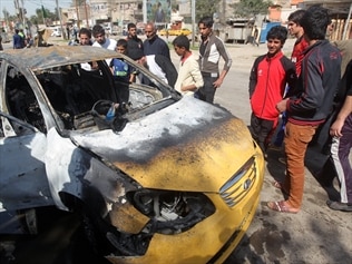 Iraqis inspect the site of a car bomb attack in Baghdad