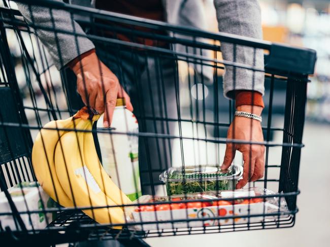 Close up of an unrecognizable man putting groceries into a shopping cart in the supermarket.  Picture: istock