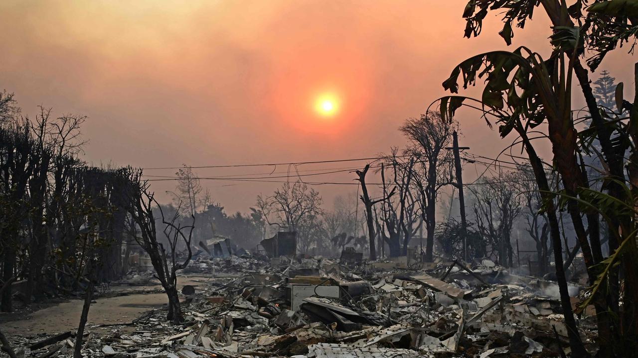 The sun is seen behind smoke above charred structures after the passage of the Palisades Fire in Pacific Palisades. Picture: Agustin Paullier/AFP