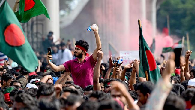 TOPSHOT - Anti-government protestors wave Bangladesh's national flag as they celebrate at Shahbag area, near Dhaka university in Dhaka on August 5, 2024. Protests in Bangladesh that began as student-led demonstrations against government hiring rules in July culminated on August 5, in the prime minister fleeing and the military announcing it would form an interim government. (Photo by Munir UZ ZAMAN / AFP)