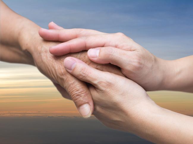 Caregiver, carer hand holding elder hand in hospice care with sky sunset background. Euthanasia  Philanthropy kindness to disabled concept.