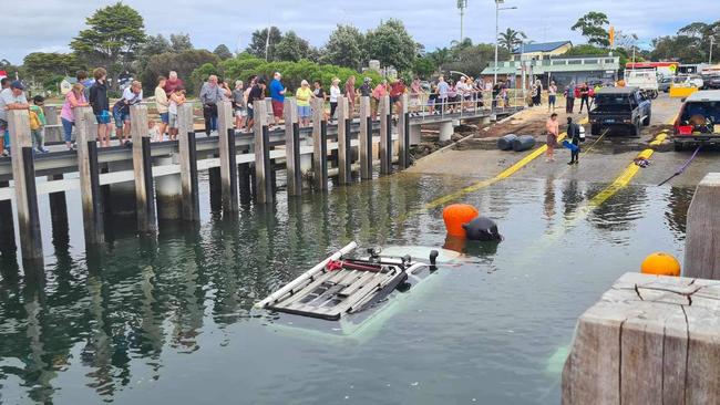 The crowd watches over the Rhyll boat ramp on Thursday morning as the submerged Toyota Hilux is pulled out of the water. Picture: Supplied/Kate Crumpet